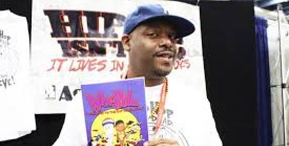 Adrian "Age" Scott, comic book artist holding up his comic at a comic con
